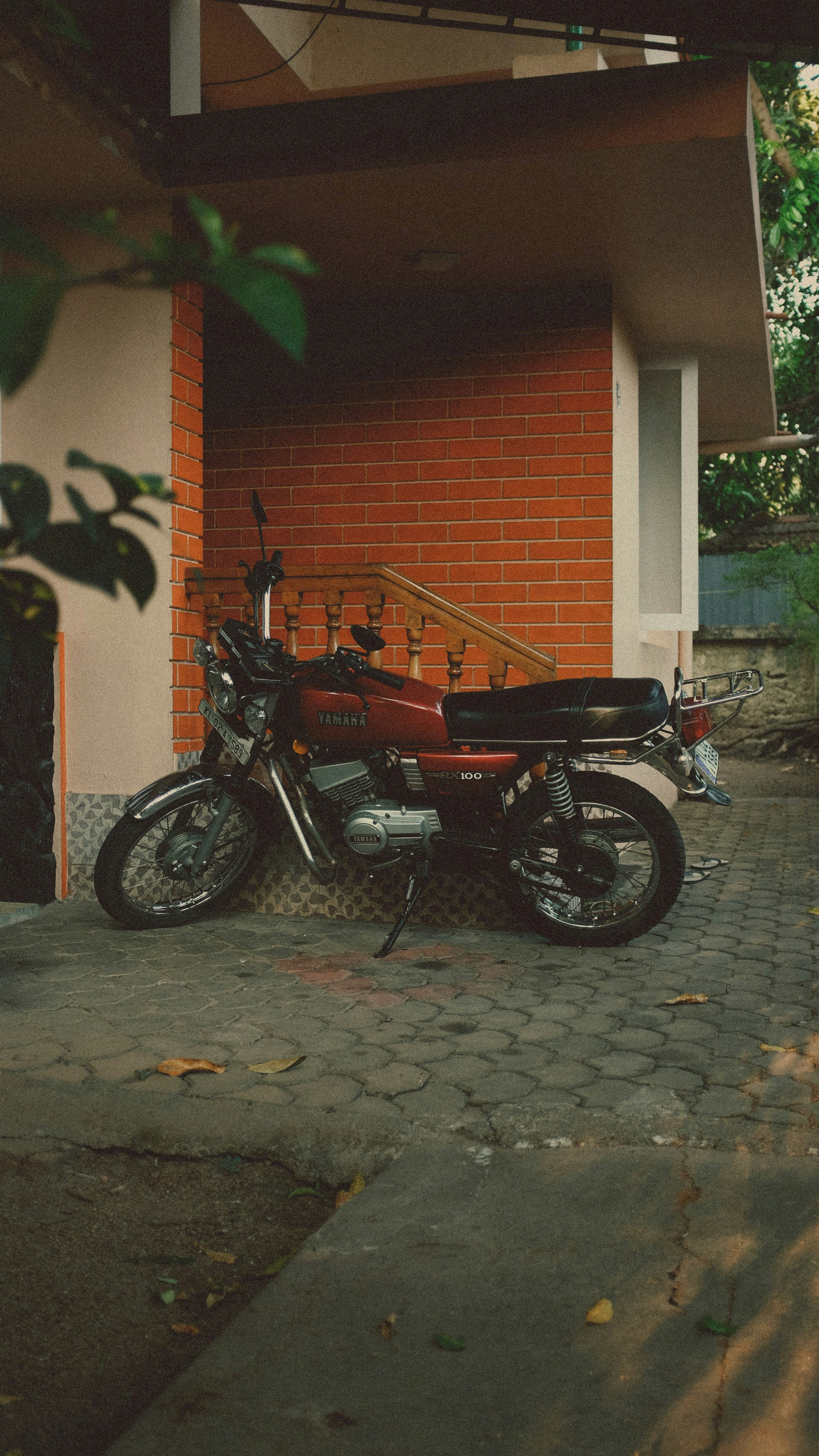 red and black motorcycle parked beside brown brick wall